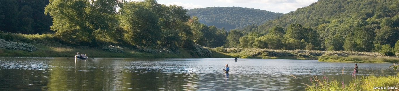 three fisher people wading in the river and a rowboat